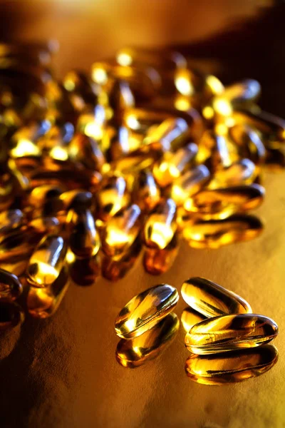 Fish oil capsules on a gold background. Omega-3, vitamin D, supplements. Healthy lifestyle.