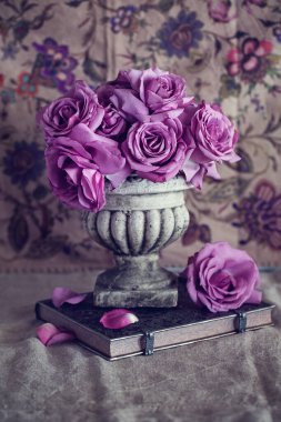 Taze güllerle dolu bir hayat. Koyu kahverengi arka planda vazoda duran güzel mor güller. .