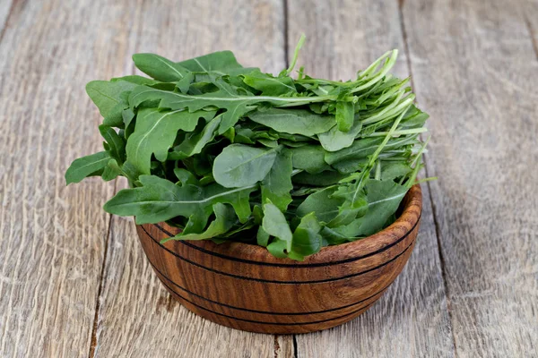 Ahşap kase üzerinde taze yeşil arugula yaprakları, — Stok fotoğraf