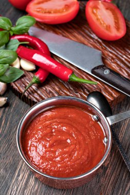 Sarımsaklı domates sosu ve ahşap bir masada fesleğen.