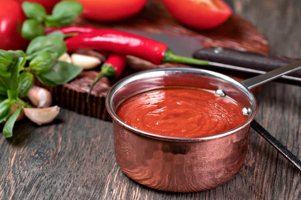 木のテーブルの上の鍋にニンニクとバジルのトマトソース — ストック写真