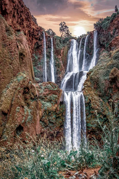 Una vista de abajo hacia arriba de la cascada rodeada de hierba verde — Foto de Stock