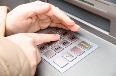 Kadın eli ATM 'ye şifre giriyor.
