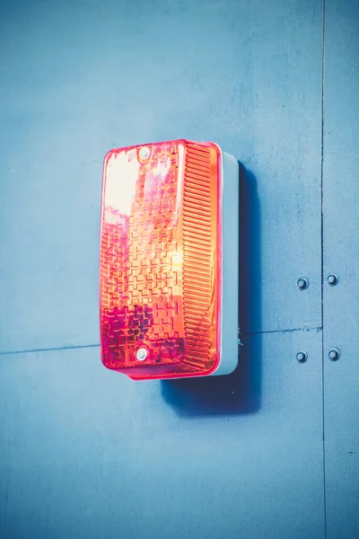 青い塗装された壁にぶら下がっている赤い注目の光の垂直ショット — ストック写真