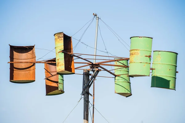 太陽の光の下で青空を背景に古い錆びた樽で作られた手工業用風車 — ストック写真
