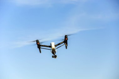 Mavi gökyüzünde uçan bir dron.