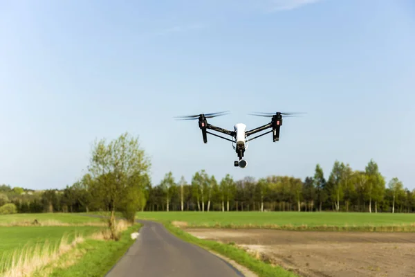 Flying drone over an asphalt street and fields
