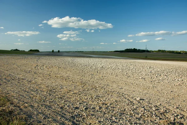 Sürülmüş alan, ufuk ve beyaz bulutların üzerinde mavi bir gökyüzü