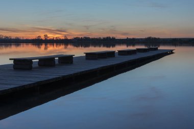 Banklar, sakin bir göl günbatımı ile uzun bir köprü