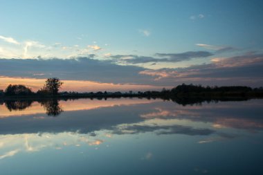 Göl, kıyı ve bulutlar su yansıma güneş battıktan sonra ağaçlar, gece
