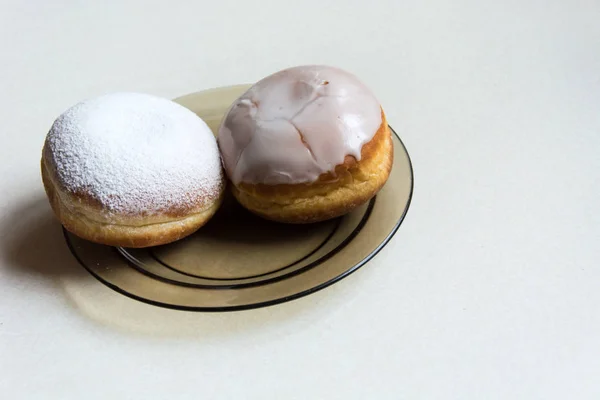 Donuts with icing and powdered sugar on a plate - closeup