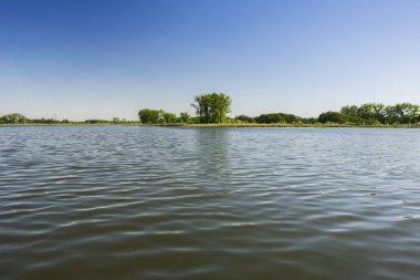 Dalgalar üzerinde göl, kıyı ve mavi gökyüzü