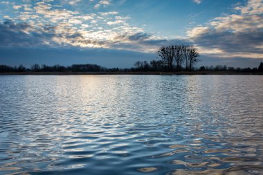 Vurgulanan Bulutların arasından güneş sakin göl ve reflecti