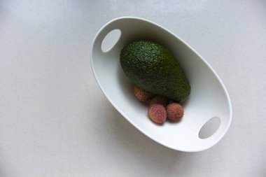 Beyaz bir kapta yeşil avokado ve litchi meyve