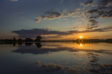 Sakin bir göl ve renkli gökyüzü üzerinde gün batımı