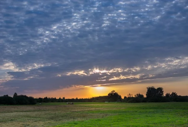 El sol poniente y las nubes azules sobre el prado — Foto de Stock