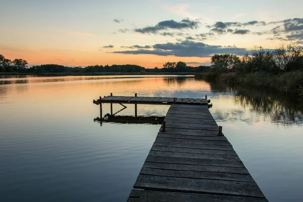 Um cais em um lago calmo e o céu após o pôr do sol — Fotografia de Stock