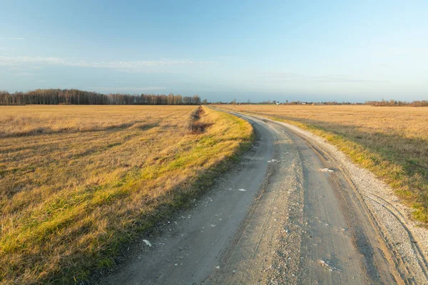 Çayırların arasından geçen eğri şekilli toprak bir yol, Aralık ayının ılık günü