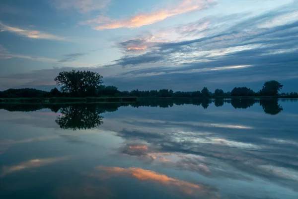 Spiegelen van de avondwolken in het meerwater — Stockfoto