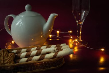 Porselen çaydanlık ve Noel ışıkları, kremalı cam ve tüpler.