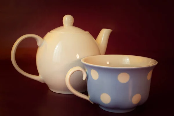 Hervidor de porcelana con taza de té, fondo granate — Foto de Stock