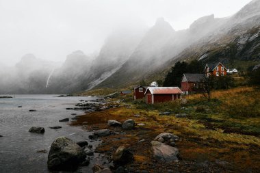 Terk edilmiş köy kırmızı ahşap evler ön ve dağlar ve okyanusun içinde belgili tanımlık geçmiş ile Lofoten Adaları Norveç'te Vindstad.      