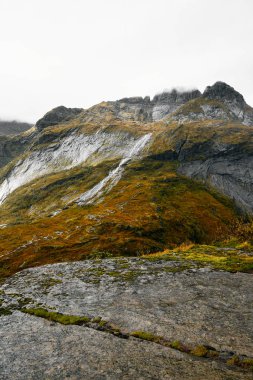 Bir vadiye bir şelale ve göl ile Lofoten Adaları Norveç dağlarında bir uçurumun kenarından görüntüleyin. Spot Solvagen dağlarda yakınındaki Kuzey Norveç'te bulunmaktadır. Eylül ayında parlak, yağmurlu ve soğuk bir gün değil. Şelale            