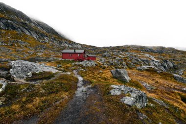 Norveç 'teki Lofoten 'deki dağlarda bulunan uzak kırmızı ahşap kabine giden yürüyüş parkuru. Kabin Munken (Moskenesoy) Dağı 'nda yer almaktadır ve Munkebu denir. Peyzaj kayalar, taşlar ve portakal çim ve yosun oluşur.