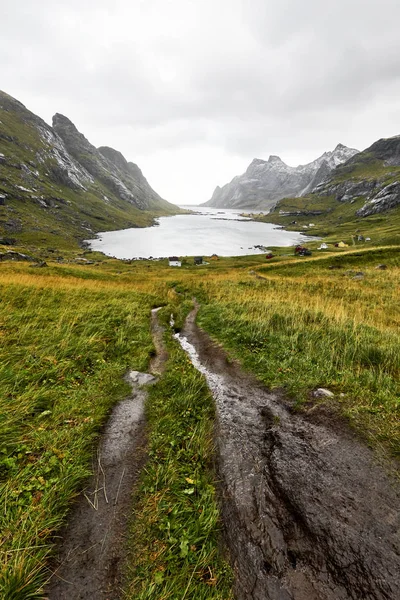 Norveç'te Lofoten Adaları'nda Bunes Beach ve Vinstad yakınlarındaki dağlar ve küçük bir köy le çevrili güzel bir koya giden yürüyüş parkuru
