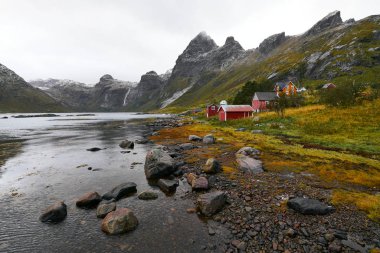 Norveç'te Lofoten Adaları arka planda dağlar ile Vinstad kıyısında uzak bir eski balıkçı köyüpanoramik görünümü.