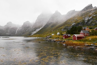 Norveç'te Lofoten Adaları arka planda dağlar ile Vinstad kıyısında uzak bir eski balıkçı köyüpanoramik görünümü.