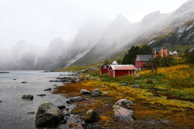 Norveç'te Lofoten Adaları arka planda dağlar ile Vinstad kıyısında uzak bir eski balıkçı köyüpanoramik görünümü.