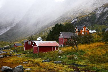 Norveç'te Lofoten Adaları arka planda dağlar ile Vinstad kıyısında uzak bir eski balıkçı köyüpanoramik görünümü.