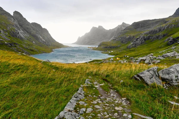 Norveç'te Lofoten Adaları'nda Bunes Beach ve Vinstad yakınlarındaki dağlar ve küçük bir köy le çevrili güzel bir koya giden yürüyüş parkuru