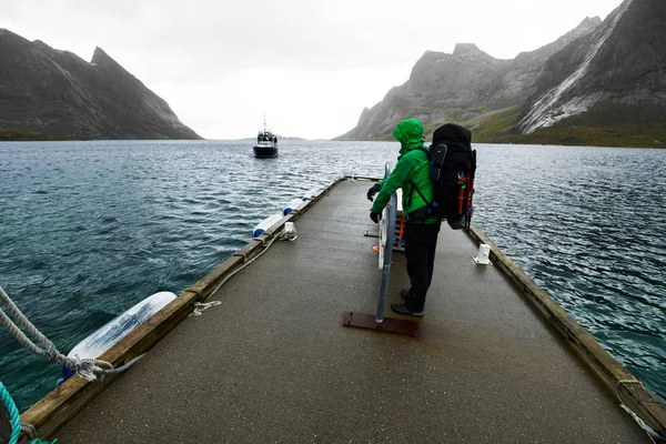 Norveç'te Lofoten Üzerinde Vinstad Reine götürmek için gelen feribot teknesi için bir iskelede bekleyen bir sırt çantası ile adam