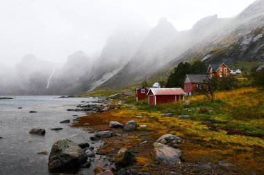 Norveç'te Lofoten Adaları arka planda dağlar ile Vinstad kıyısında uzak bir eski balıkçı köyüpanoramik görünümü.