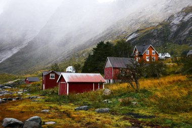 Norveç'te Lofoten Adaları arka planda dağlar ile Vinstad kıyısında uzak bir eski balıkçı köyüpanoramik görünümü.