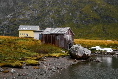 Kış aylarında Norveç'te Lofoten Adaları kıyısında çeşitli kabin manzara manzara. Evlerin arkasında karla kaplı dağlar var..