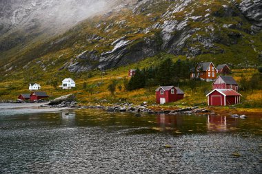 Norveç'te Lofoten Adaları arka planda dağlar ile Vinstad kıyısında uzak bir eski balıkçı köyüpanoramik görünümü.
