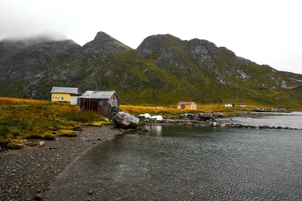 冬季挪威罗弗顿群岛海岸几间小屋的风景全景 房子后面是白雪覆盖的群山 — 图库照片