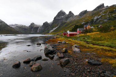 Norveç'te Lofoten Adaları arka planda dağlar ile Vinstad kıyısında uzak bir eski balıkçı köyüpanoramik görünümü.