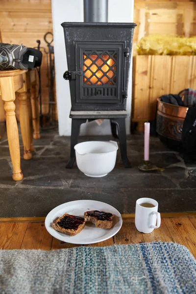 Bir odun sobasında bir ateşin önünde tost ve çay la oturmak.