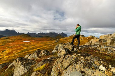 Lofoten Adaları arka planda altın manzaralar ile bir fincan kahve tutan adam
