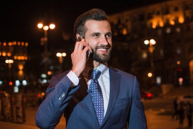 Güzel telefon. Yakışıklı genç adam açık havada duran ise cep telefonu üzerinde konuşurken portresi