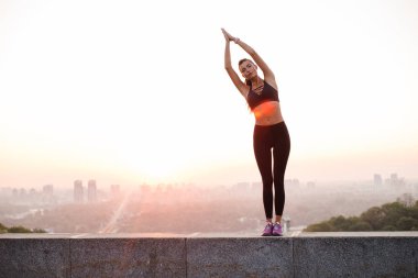 Bu şehir ile dengede. Genç güzel kadın spor giyim sanayi kenti görünümü karşı dururken yoga yaparken uygun