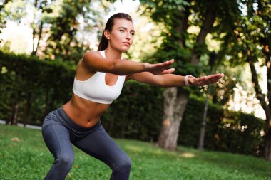 Büyük ağız kavgası. Genç güzel kadın yeşil parkta egzersiz spor giyim uygun