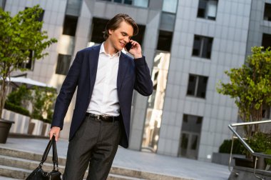 Beş dakika sonra görüşürüz. Onun çantası taşıyan ve açık havada duran ise onun smartphone kullanarak yakışıklı delikanlı