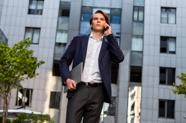 İş üstünde bir gitmek. Onun laptop taşıyan ve açık havada duran ise onun smartphone kullanarak yakışıklı delikanlı