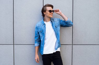 Ne var duymak? Yakışıklı genç adam uzakta ayakta açık havada süre gülümseme ile seyir güneş gözlüğü