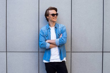 Sırdaş ve yakışıklı. Yakışıklı genç adam uzakta ayakta açık havada süre gülümseme ile seyir güneş gözlüğü